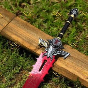May include: A detailed fantasy sword with a red blade and intricate silver and black hilt. The blade has etched inscriptions. The sword rests on a wooden surface against a backdrop of green grass.