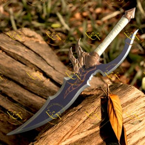 May include: A fantasy-style dagger with a curved blade and ornate hilt. The blade is dark purple with gold accents, and the hilt features a bronze-colored guard and a white handle. The dagger rests on a weathered wooden surface.