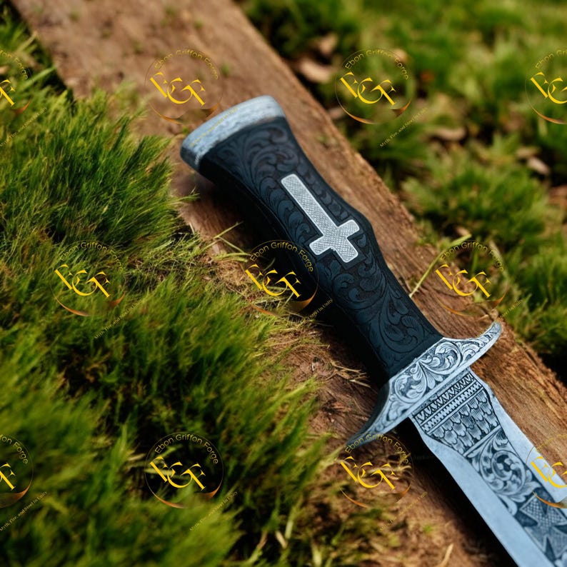 May include: A detailed close-up of a dagger with a black handle featuring an engraved cross and ornate floral patterns. The silver blade is also intricately engraved. The dagger rests on a wooden surface with green moss.