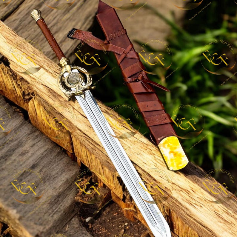 May include: A decorative sword with a silver blade and a gold-colored hilt, resting on a wooden surface. The handle is wrapped in brown leather. A brown leather sheath with a yellow tip is also present.