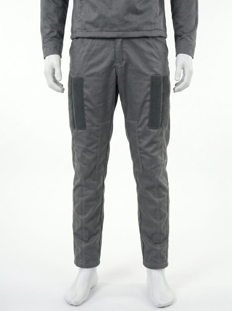 May include: Gray, two-piece outfit. The long-sleeved top and pants are a matching shade of gray. The pants have two rectangular patches on the front of each leg. The outfit is displayed on a mannequin.