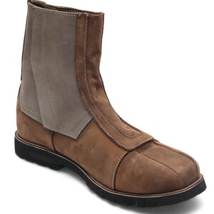 K&ouml;nnte beinhalten: Ein brauner Lederstiefel mit schwarzer Sohle. Der Stiefel hat ein zweifarbiges Design mit einem helleren grauen Einsatz am oberen Schaft und einem dunkleren Braun am Rest. Wei&szlig;e N&auml;hte akzentuieren die N&auml;hte.