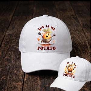 May include: Two white baseball caps featuring cartoon sweet potato graphics. The larger cap displays a sweet potato character with the text "SHE IS MY sweet POTATO" in red and orange. The smaller cap shows a sweet potato character with "HE IS MY sweet POTATO".