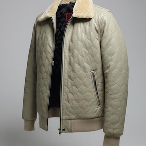 Puede incluir: Chaqueta de cuero acolchada beige claro con cuello de piel sintética color crema. La chaqueta tiene cierre de cremallera, dobladillo y puños de canalé. El forro interior es negro.
