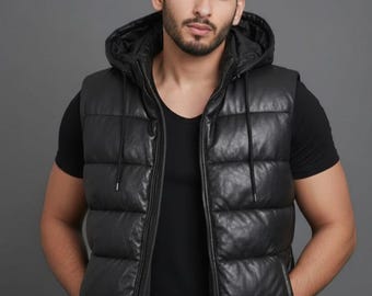 Può includere: Gilet nero con cappuccio e zip. Il gilet ha un design trapuntato e due tasche frontali. Il modello indossa una maglietta nera sotto. Il gilet è realizzato in materiale simile alla pelle.