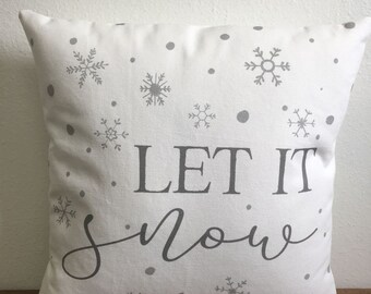May include: White throw pillow with a gray snowflake pattern and the text "Let it snow" in gray lettering.