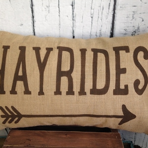 May include: A brown burlap pillow with the word "HAYRIDES" printed in brown letters. An arrow is printed below the text.