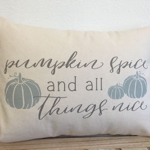 May include: A beige throw pillow with the text "pumpkin spice and all things nice" in gray script. The pillow features three gray pumpkins with stems.