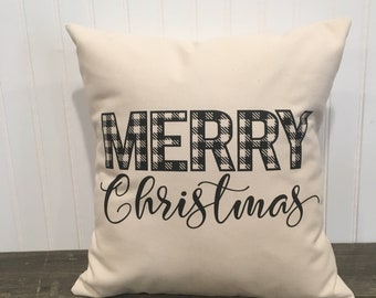 May include: A white throw pillow with the words "Merry Christmas" printed in black. The word "Merry" is in black and white buffalo plaid.