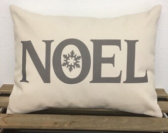 May include: A white pillow with the word "NOEL" printed in gray with a snowflake in the center of the "O".