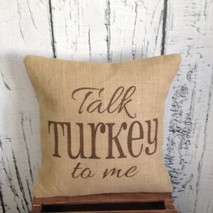 May include: A brown burlap pillow with the text "Talk Turkey to me" printed in brown on the front.