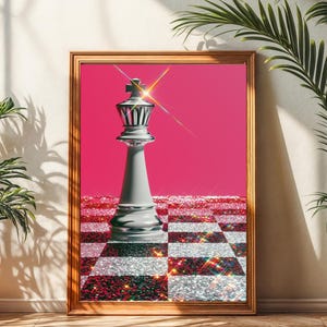 Könnte beinhalten: Gerahmter Kunstdruck mit einem grauen Schachkönig auf pinkfarbenem Hintergrund. Die Schachbrettbasis ist eine Mischung aus silbernen und roten Glitzer. Das Kunstwerk befindet sich in einem goldenen Rahmen, mit zwei Topfpflanzen.