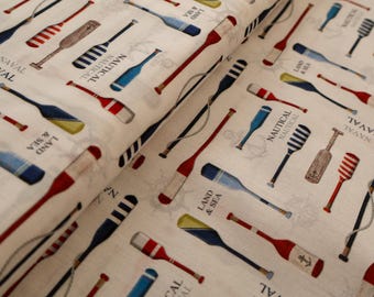 Tela de algodón beige con estampado náutico de remos, ideal para decoración y confección de ropa. Se vende por metro.