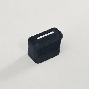 May include: A black rectangular control knob featuring a horizontal white indicator line on the top surface and a series of parallel horizontal ridges along the side faces to provide a textured grip for manual adjustment of electronic equipment.