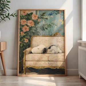 May include: A framed print featuring a cartoon dog sleeping on a floral patterned sofa. The background shows a wall with a floral design and a window. The frame is made of wood. The color palette includes beige, pink, and blue.