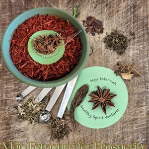 Può includere: Una ciotola turchese piena di pot-pourri rosso, accompagnata da cucchiai dosatori e varie erbe. È presente anche un cerchio verde chiaro con il testo "Mojo Botanicals" e "Healthy Spirit Ventures". Le parole "Mojo Potpourri for Prosperity" sono in basso.