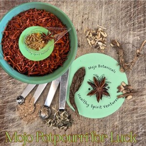 Può includere: Una ciotola turchese piena di pot-pourri marrone-rossastro, un piccolo cucchiaio e cucchiai dosatori. Un cerchio verde con testo e anice stellato è nelle vicinanze. Il testo "Mojo Potpourri for Luck" è in basso.