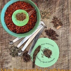 Può includere: Una ciotola verde piena di pot-pourri arancione, un piattino verde con erbe e cucchiai dosatori. Erbe e corteccia aggiuntive sono sparse. Il testo "Mojo Potpourri for Confidence" è in basso.