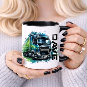 Peut inclure: Mug en céramique blanche avec intérieur et anse noirs. La tasse présente une illustration colorée d'un semi-remorque avec le nom "DAVE" imprimé verticalement sur le côté. Le camion est bleu et vert, avec des éclaboussures de peinture bleue et verte.