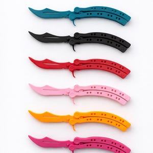 May include: A collection of six butterfly knives in various colors: teal, black, red, pink, orange, and magenta. Each knife features a curved blade and a handle with a series of small holes. The knives are arranged vertically against a white background.
