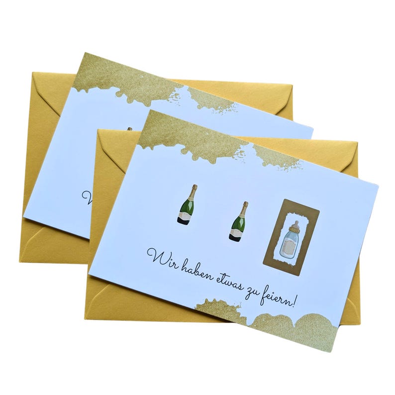 May include: Greeting cards with gold accents and matching envelopes. The cards feature illustrations of champagne bottles and a baby bottle, with the text "Wir haben etwas zu feiern!" in a script font.