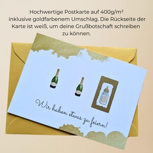 May include: A white postcard with gold accents and a gold envelope. The card features illustrations of champagne bottles and a baby bottle, with the text "Wir haben etwas zu feiern!"