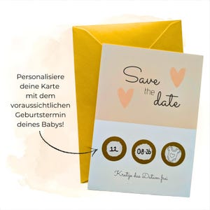 Könnte beinhalten: Eine 'Save the Date'-Karte mit pfirsichfarbenem Hintergrund und zwei pfirsichfarbenen Herzen. Der Text 'Save the date' ist in schwarzer Schrift geschrieben. Darunter befinden sich drei goldene Kreise mit Zahlen und einem Baby-Strampler-Symbol. Ein gelber Umschlag befindet sich hinter der Karte.