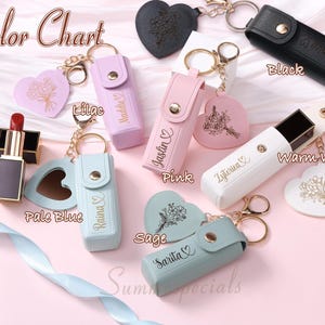 May include: A color chart featuring lipstick holders and heart-shaped keychains in various colors, including black, pink, lilac, and warm white. Each holder has a snap closure and a gold keychain. The text "Color Chart" is at the top.
