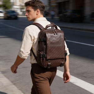 May include: A brown leather backpack with multiple compartments and adjustable straps. The backpack has a top handle and is secured with buckles. The bag is carried by a person walking on a city street.