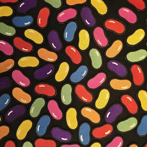 Könnte beinhalten: Eine Sammlung von gestickten Aufnähern in Form von Geleebohnen in verschiedenen Farben wie Rot, Orange, Gelb, Grün, Blau, Lila und Pink. Jeder bohnenförmige Aufnäher hat ein kleines weißes Highlight und einen schwarzen gestickten Rand.