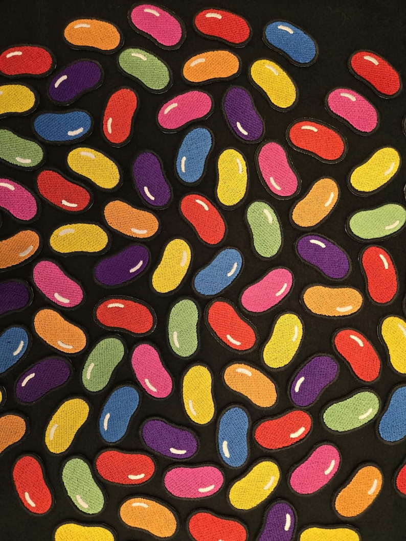 K&ouml;nnte beinhalten: Eine Sammlung von gestickten Aufn&auml;hern in Form von Geleebohnen in verschiedenen Farben wie Rot, Orange, Gelb, Gr&uuml;n, Blau, Lila und Pink. Jeder bohnenf&ouml;rmige Aufn&auml;her hat ein kleines wei&szlig;es Highlight und einen schwarzen gestickten Rand.