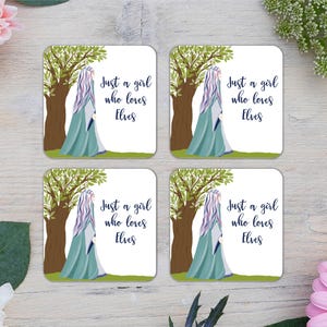 Puede incluir: Cuatro posavasos cuadrados con temática de fantasía. Cada posavasos presenta una ilustración de una figura con un vestido verde azulado y un árbol, con el texto "Just a girl who loves Elves."