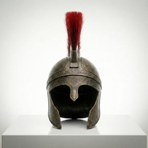 May include: A bronze-colored metal helmet featuring a weathered, antique finish with intricate embossed scrollwork patterns along the brow. The helmet is topped with a tall, upright crest made of stiff, vibrant red bristles centered on the dome.