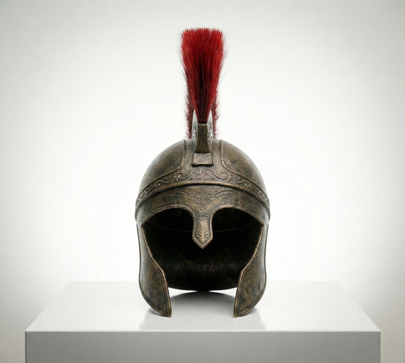 May include: A bronze-colored metal helmet featuring a weathered, antique finish with intricate embossed scrollwork patterns along the brow. The helmet is topped with a tall, upright crest made of stiff, vibrant red bristles centered on the dome.
