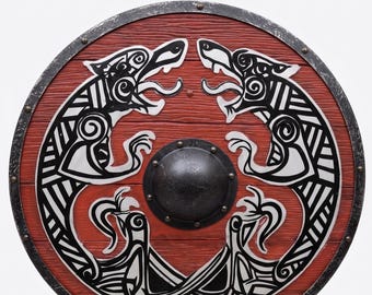 May include: A round wooden shield featuring a red textured surface with a black metal rim and a central dark metal boss. The face displays a symmetrical black and white graphic design of two stylized wolves facing each other with intricate patterns.
