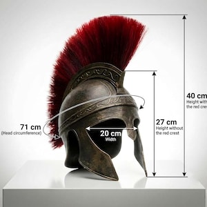 May include: A bronze-colored helmet with a tall red crest. The helmet features engraved scrollwork along the brow. Dimensions are 40 cm in total height, 27 cm in height without the crest, 20 cm in width, and 71 cm in head circumference.
