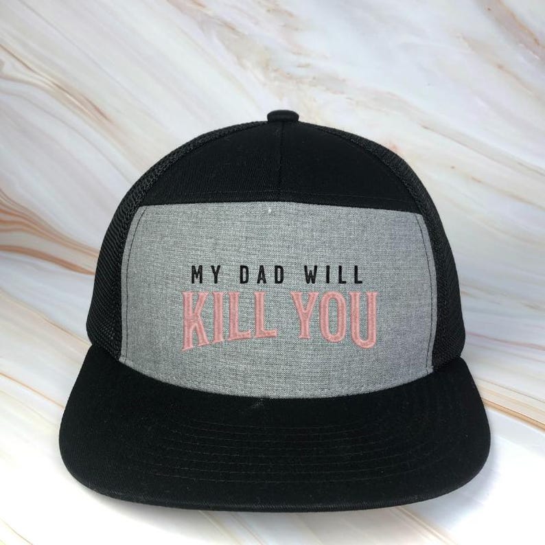 May include: Black and gray trucker hat with the embroidered text "MY DAD WILL KILL YOU" in pink. The hat features a mesh back and a curved brim. The front panel is gray.