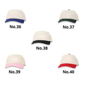 May include: Five baseball caps with a cream-colored crown and a colored brim. The brims are blue, green, black, pink, and red. Each cap has a number printed below it: No.36, No.37, No.38, No.39, and No.40.