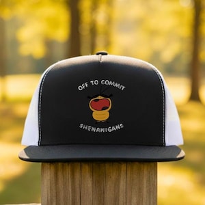 May include: Black and white trucker hat with the text "OFF TO COMMIT SHENANIGANS" and a cartoon bee graphic. The hat has a black brim and a white mesh back, perfect for casual wear.