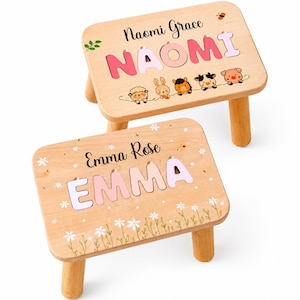 Pode incluir: Dois bancos de madeira clara com quatro pernas cada. O banco superior apresenta o nome Naomi Grace e o nome NAOMI em letras cor-de-rosa com animais. O banco inferior apresenta o nome Emma Rose e EMMA em letras cor-de-rosa com flores.