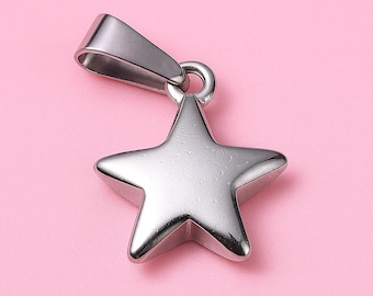May include: A polished silver star pendant with a loop for a chain. The star has five points and a rounded, three-dimensional design. The pendant is shown against a pink background.