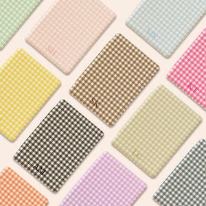 May include: A selection of rectangular notebooks with a gingham pattern in shades like pink, yellow, and brown. Each notebook is personalized with initials. The notebooks are arranged at different angles, creating a visually appealing display.