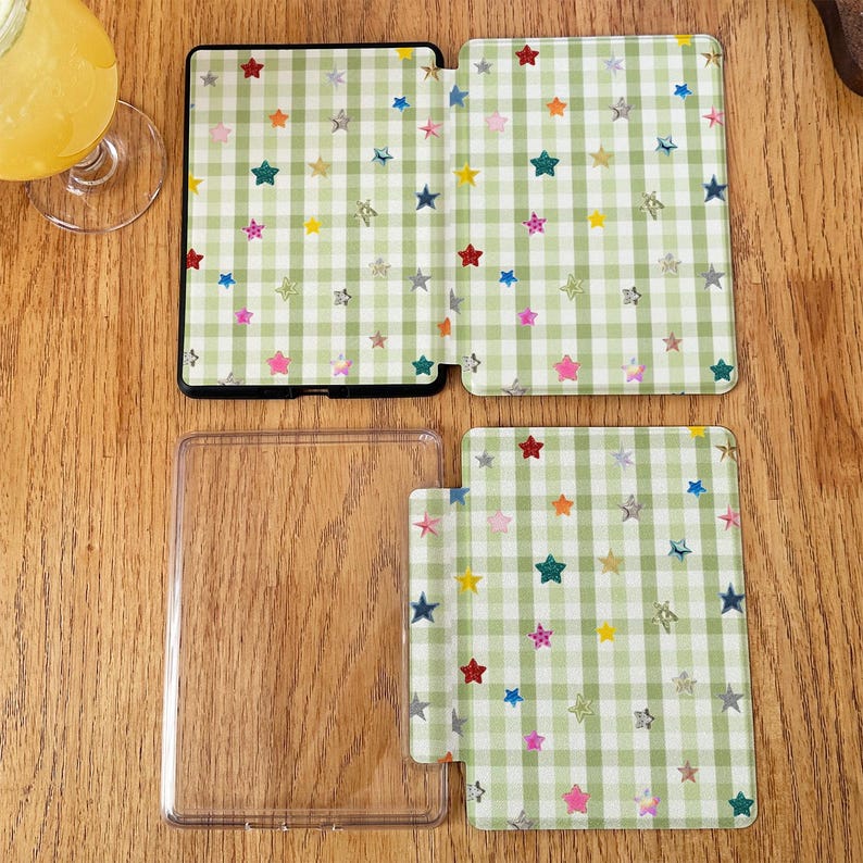May include: A clear plastic protective case for an e-reader, featuring a light green and white gingham pattern decorated with small, colorful, multi-pointed stars. The set includes a front cover, a back cover, and a separate clear frame piece.