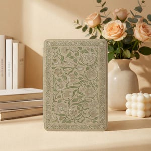 May include: A rectangular tablet case featuring a light sage green cover with an intricate, repeating floral and vine pattern in muted tones. The design includes a decorative border framing the central botanical illustration on the front panel.
