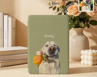 May include: A sage green e-reader cover featuring a printed image of a light-colored dog holding a yellow and orange tulip in its mouth. The name Rocky is printed in white text above the dog. The cover has a smooth, matte-textured finish.
