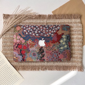 Può includere: Una custodia rigida per laptop caratterizzata da un motivo vibrante e intricato di forme organiche vorticose, punti e linee nelle tonalità del rosso, blu, giallo e nero, con un ritaglio centrale che rivela il logo Apple bianco sul coperchio.