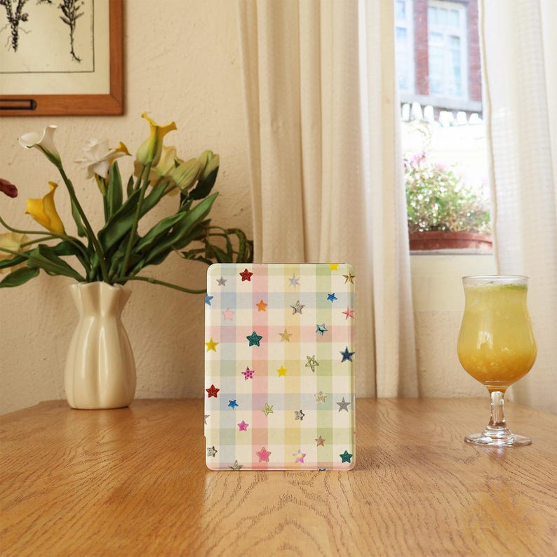 May include: A rectangular tablet case featuring a pastel plaid pattern in shades of light blue, pink, yellow, and green, decorated with small, scattered star-shaped icons in various colors including red, silver, blue, and yellow.