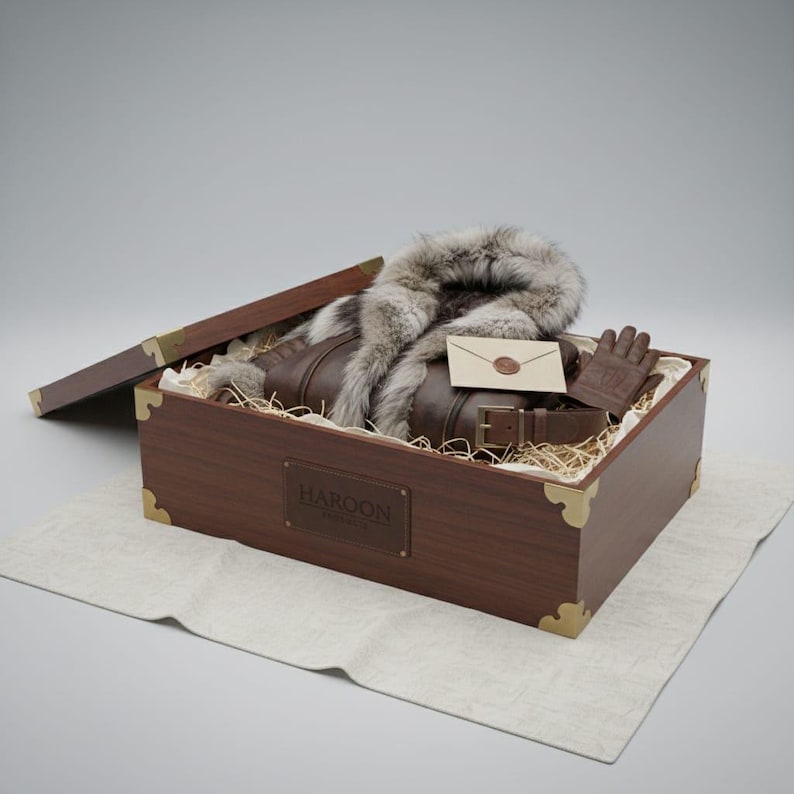 May include: A brown leather jacket with a fur collar, belt, and gloves, presented in a wooden box with the name "HAROON" on it. The box is lined with straw and has brass corner accents. An envelope with a wax seal is also included.