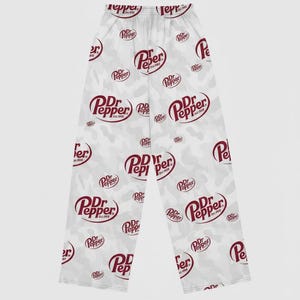 May include: White pajama pants with a repeating pattern of the Dr. Pepper logo in burgundy. The pants have a camouflage-style background with the Dr. Pepper logo scattered across the fabric.