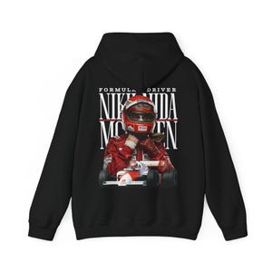 May include: Black hoodie with a graphic of Formula 1 driver Niki Lauda in his racing suit and helmet. The text "Niki Lauda" and "Formula Driver" are printed above the image in white. The hoodie has a drawstring hood and a kangaroo pocket.